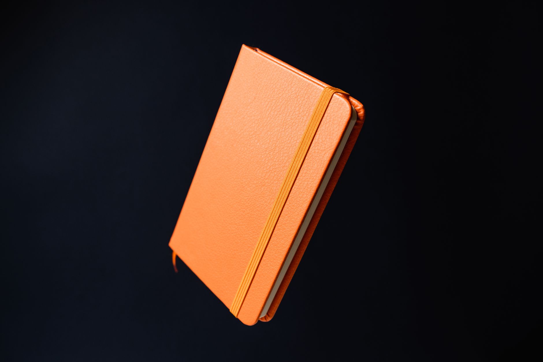 side-by-side comparison of a perfect-bound A5 booklet with square spine next to a saddle-stitch booklet open flat, both on a timber desk in