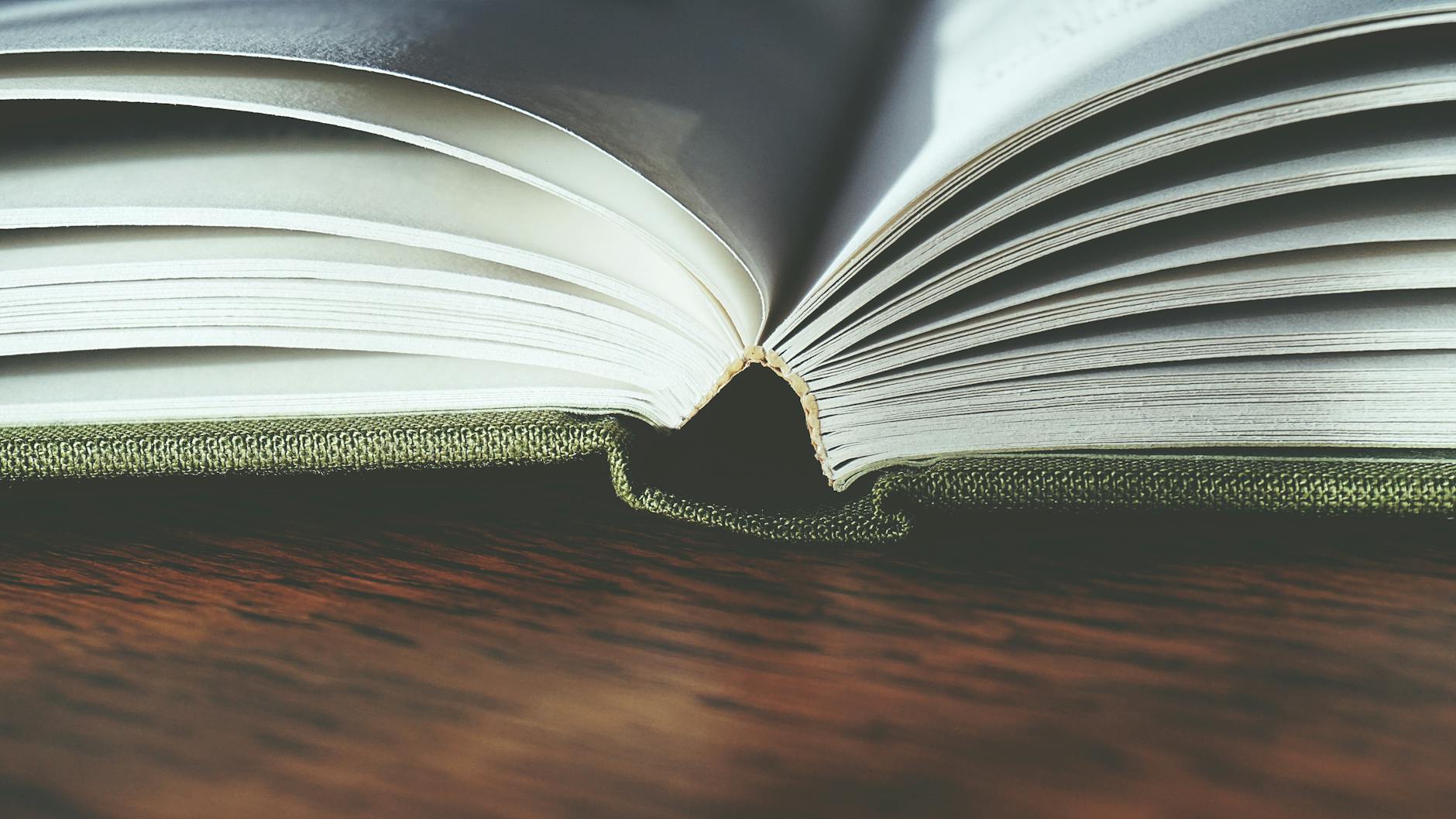 an open hardcover book standing upright on a dark timber table