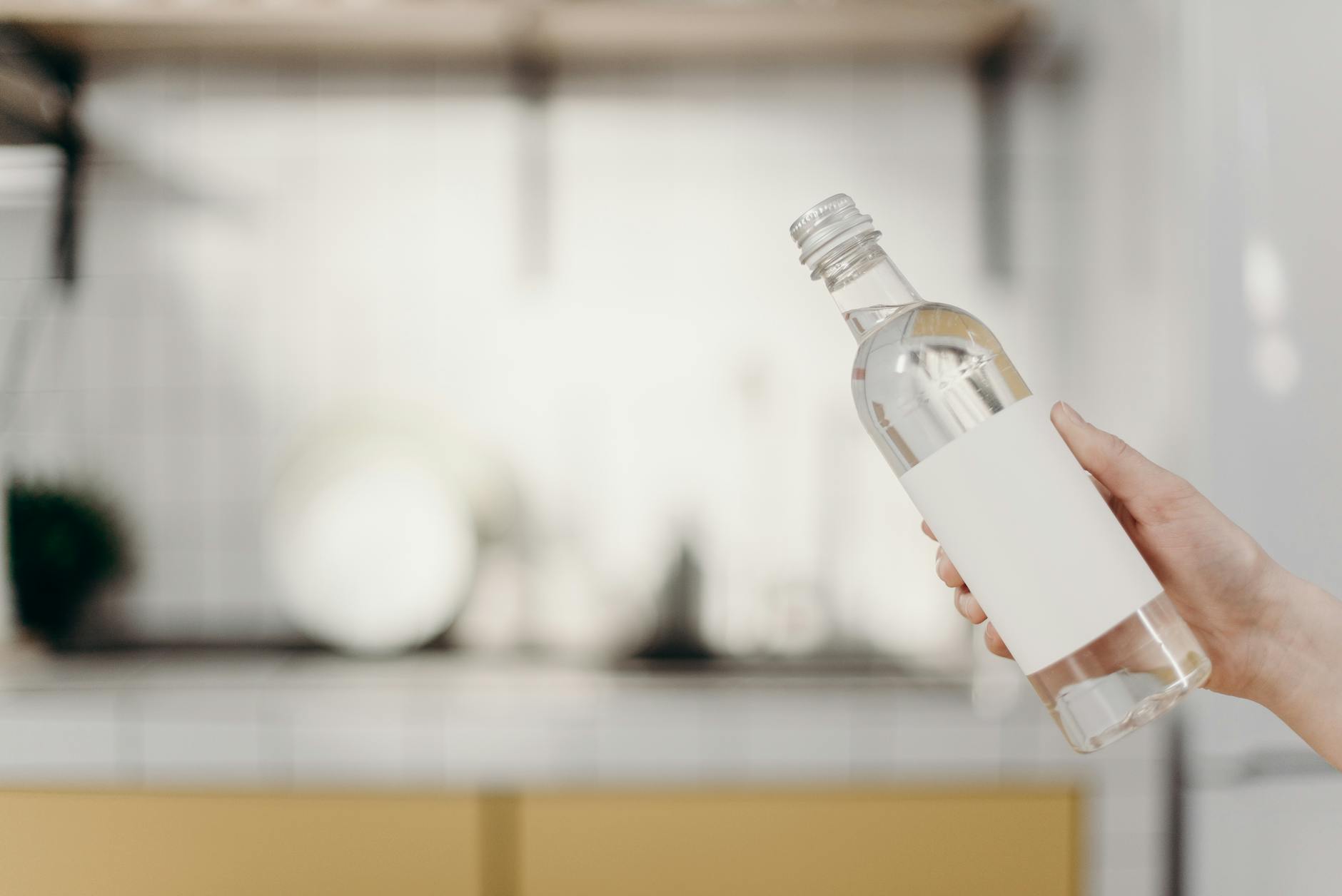 a clear glass bottle with a printed label on a kitchen bench