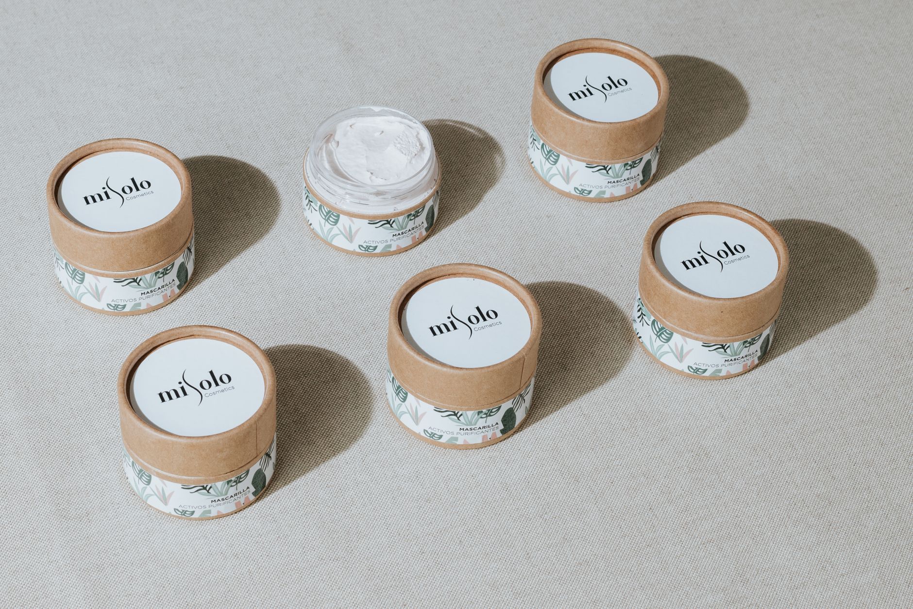 small white cosmetic jars with printed lid labels arranged on a white surface
