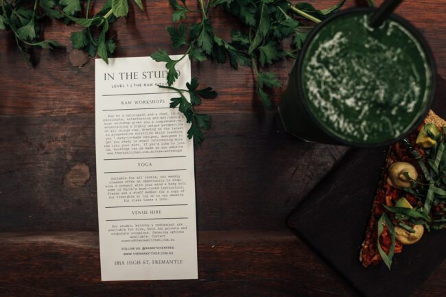a well-designed A5 event flyer laid flat on a wooden desk beside a coffee cup, showing bold headline text and a clear call-to-action button