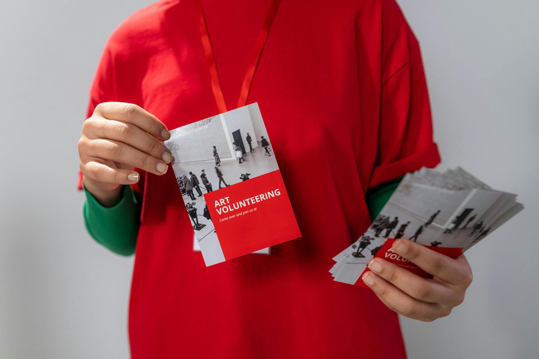 a person holding two printed promotional flyers, one in each hand
