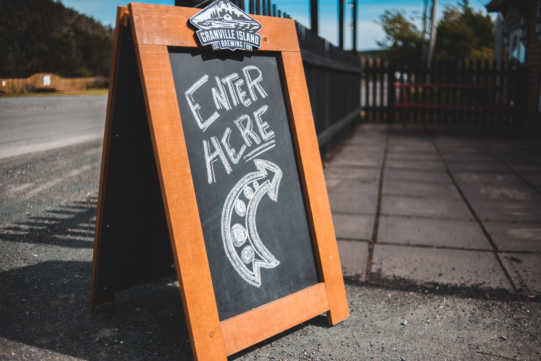 a timber A-frame chalkboard sign on the pavement outside a venue