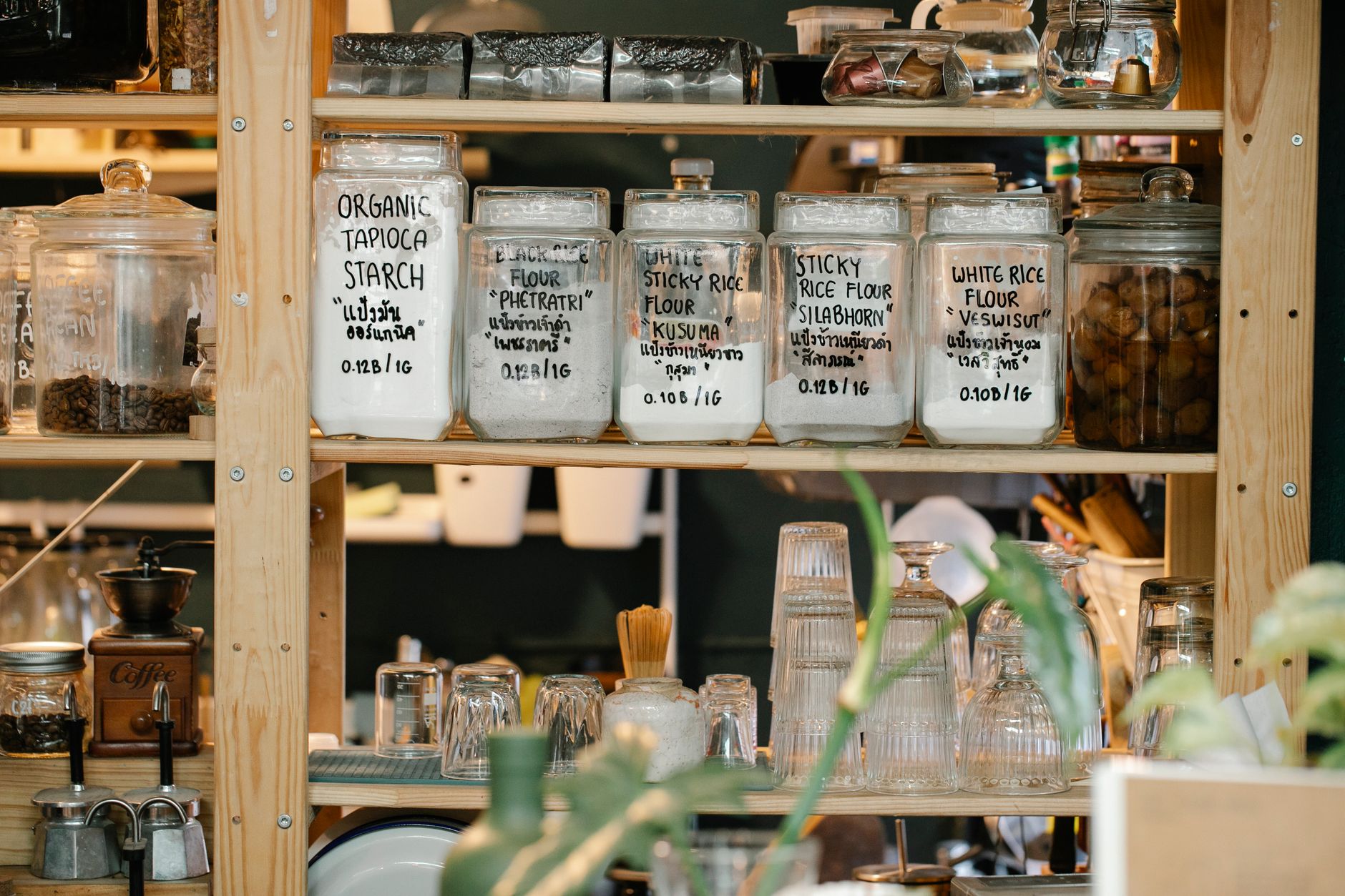 row of small glass jars with white rectangle product labels showing brand name and product details, arranged neatly on a white shelf in a