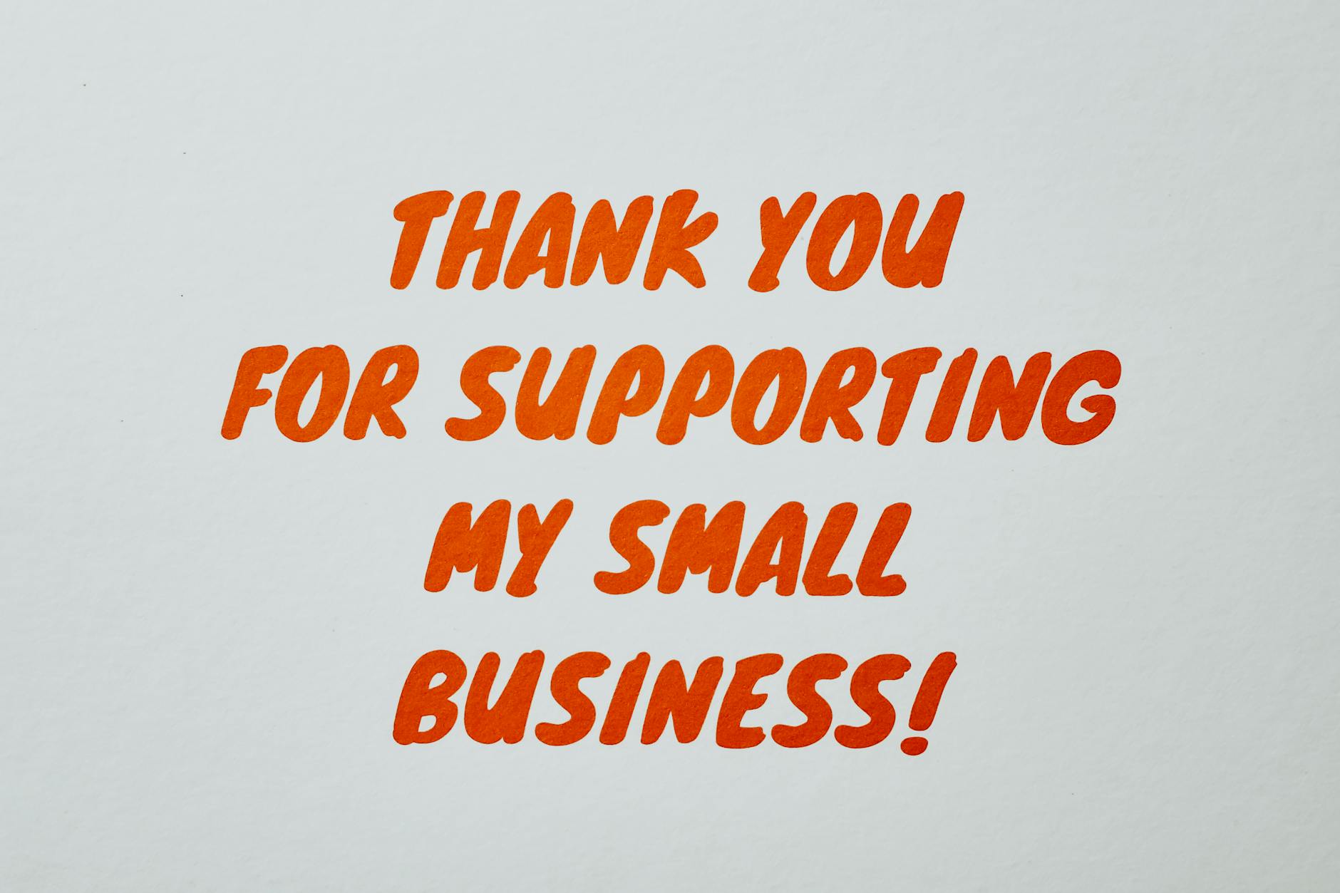 a small printed thank-you card in business card format propped against a product box, showing a short personalised message and a social