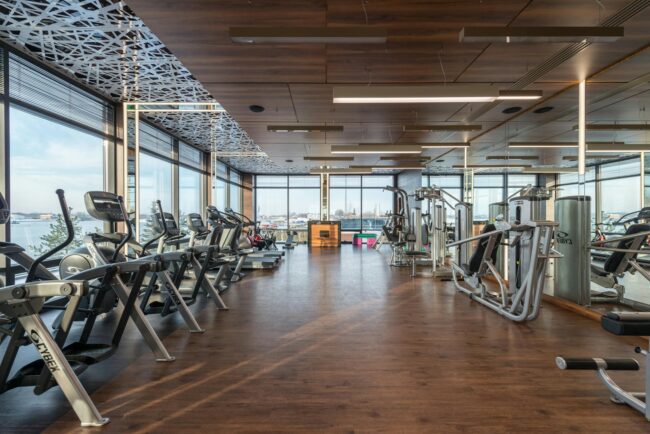 a bright modern gym floor with rows of fitness equipment