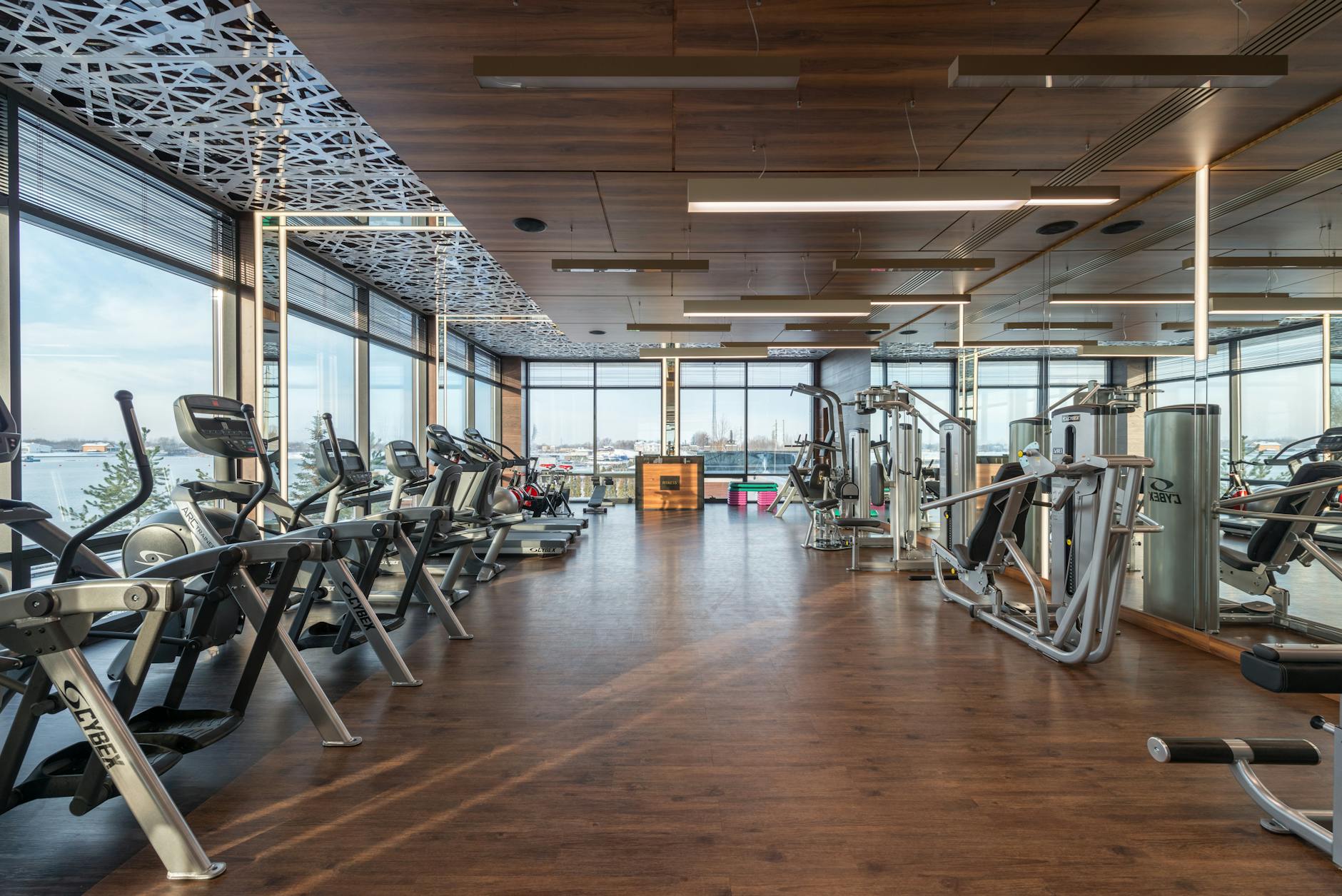 a bright modern gym floor with rows of fitness equipment