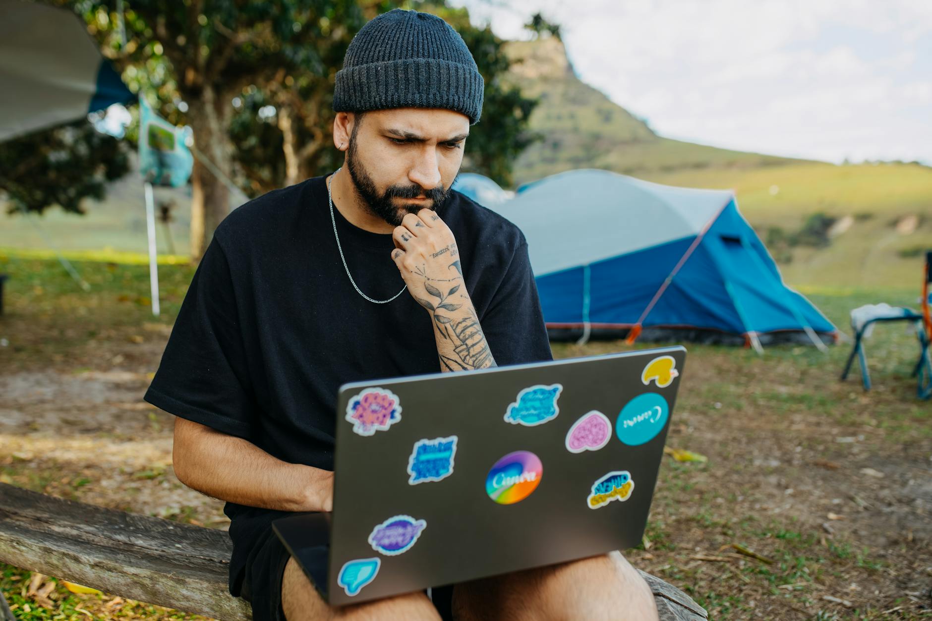 a laptop lid decorated with colourful die-cut stickers at a campsite