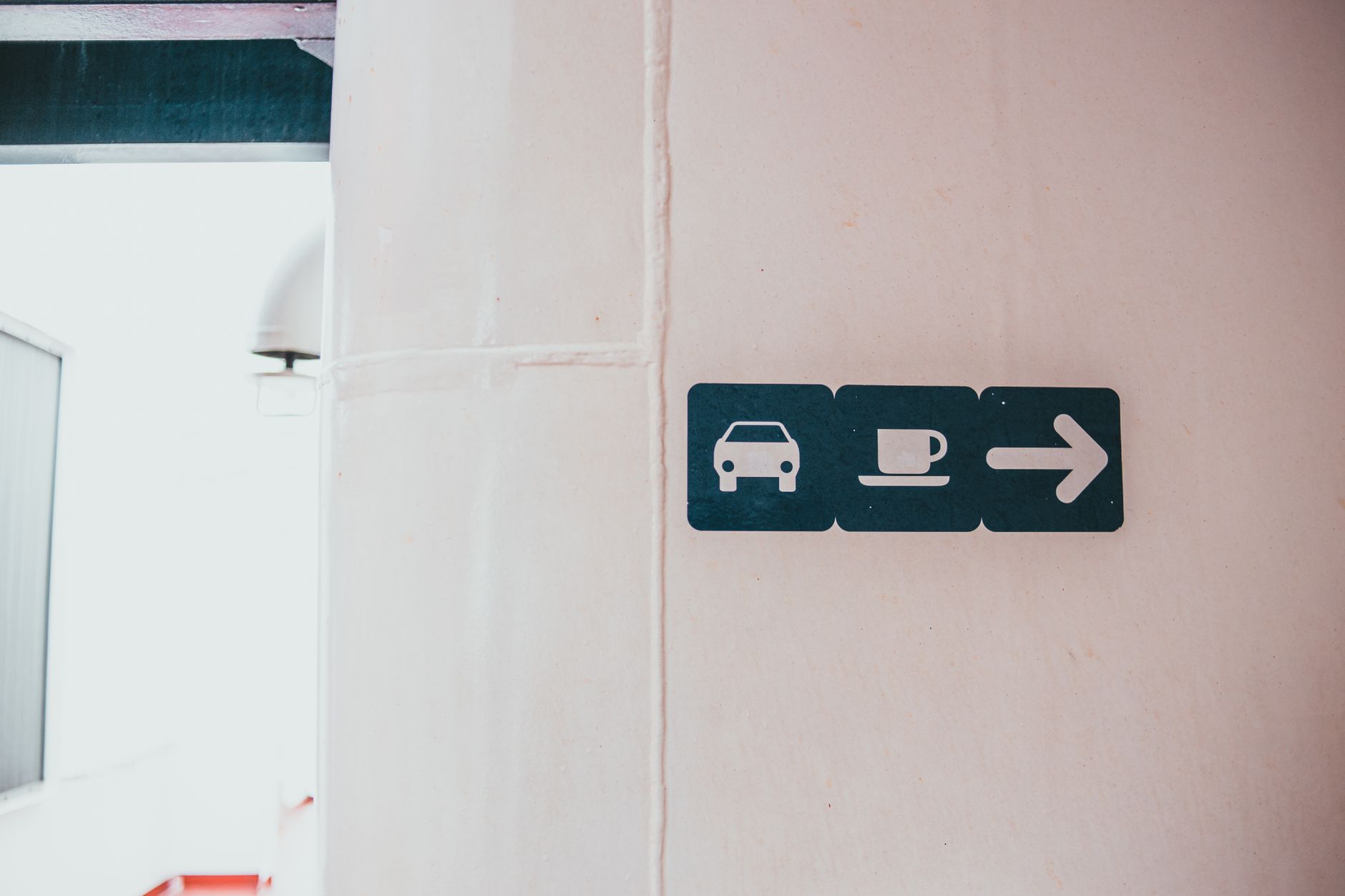 a wayfinding sign with directional icons mounted in a corridor