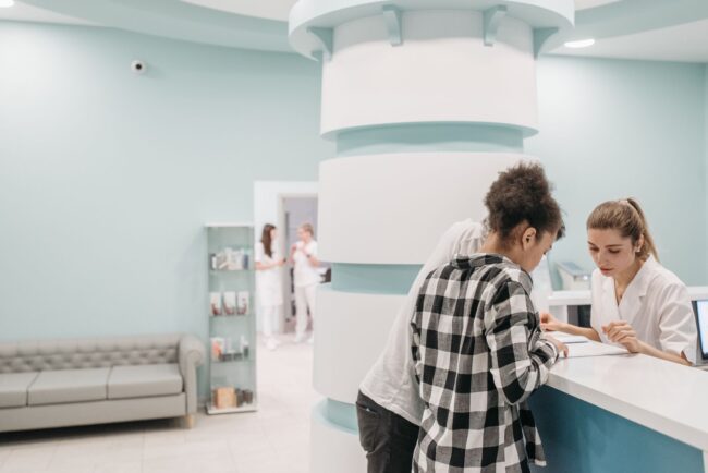 patients holding printed forms at a medical centre reception desk