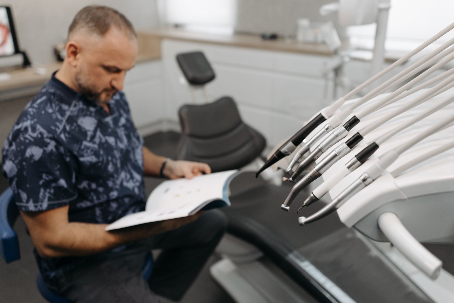 a patient reading a printed booklet beside a dental chair