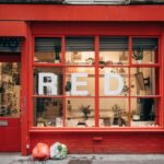 A retail shopfront window displaying bold red and yellow EOFY sale signage with percentage-off posters, A-frame sign on the footpath, and