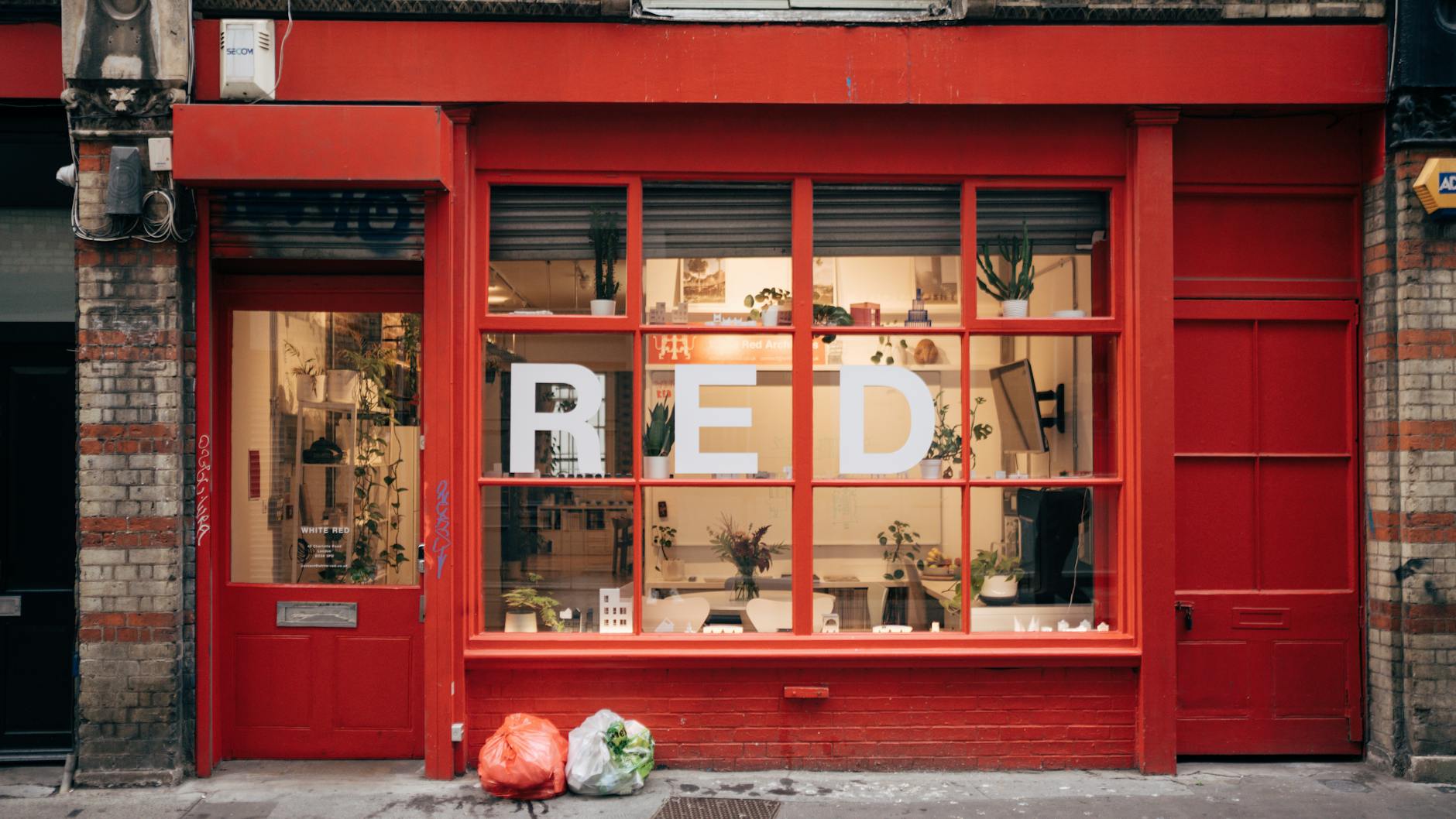 A retail shopfront window displaying bold red and yellow EOFY sale signage with percentage-off posters, A-frame sign on the footpath, and