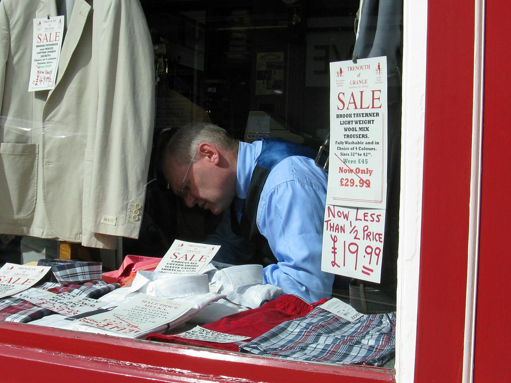 a shopkeeper arranging sale signage in a retail store window