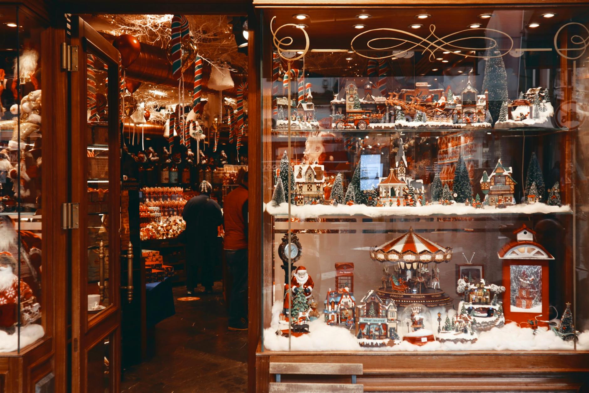 Christmas window decal on a retail storefront showing a festive 'Season's Greetings' design with decorative stars and a sale callout