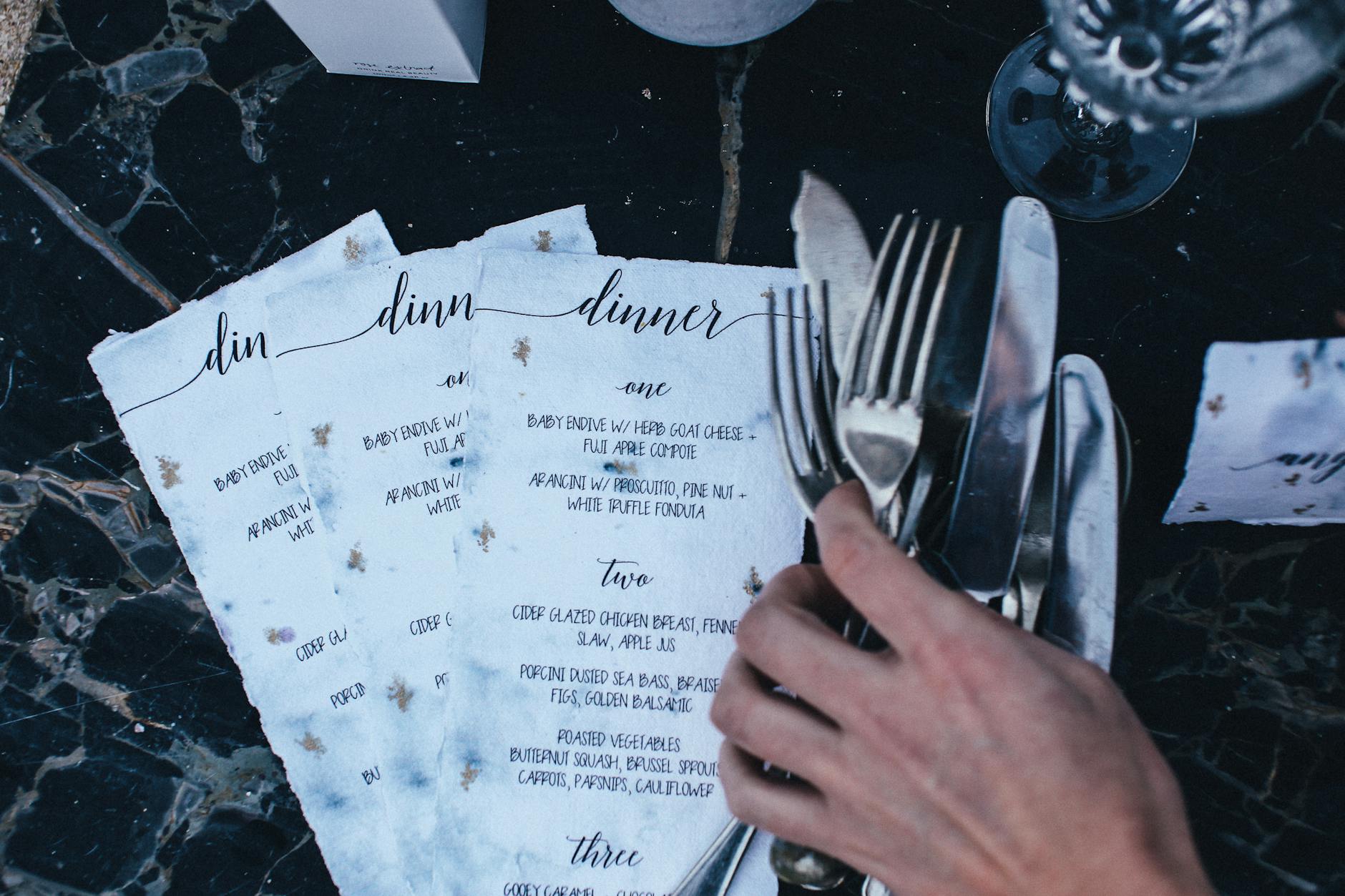 A printed Christmas function menu on a restaurant table with a festive dark green design, folded format, surrounded by Christmas decorations
