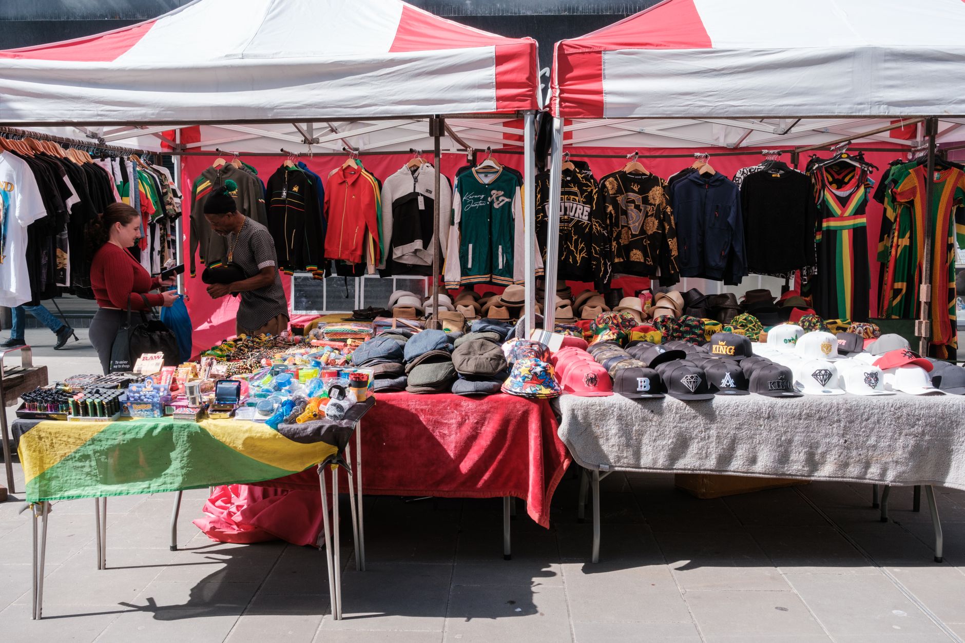 a market stall with a branded A-frame sign at the front showing product names and prices, with corflute signs attached to the stall frame
