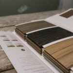 side-by-side samples of corflute, foam-PVC and acrylic sign materials laid flat on a workbench, showing cross-section thickness differences