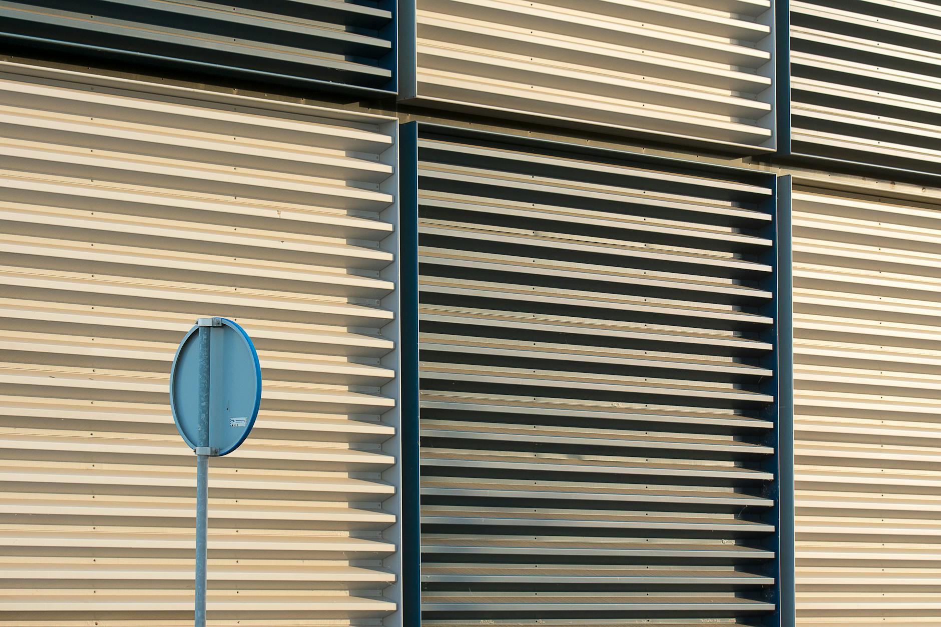 a metal louvred signage panel on a building facade with a round sign mounted on it