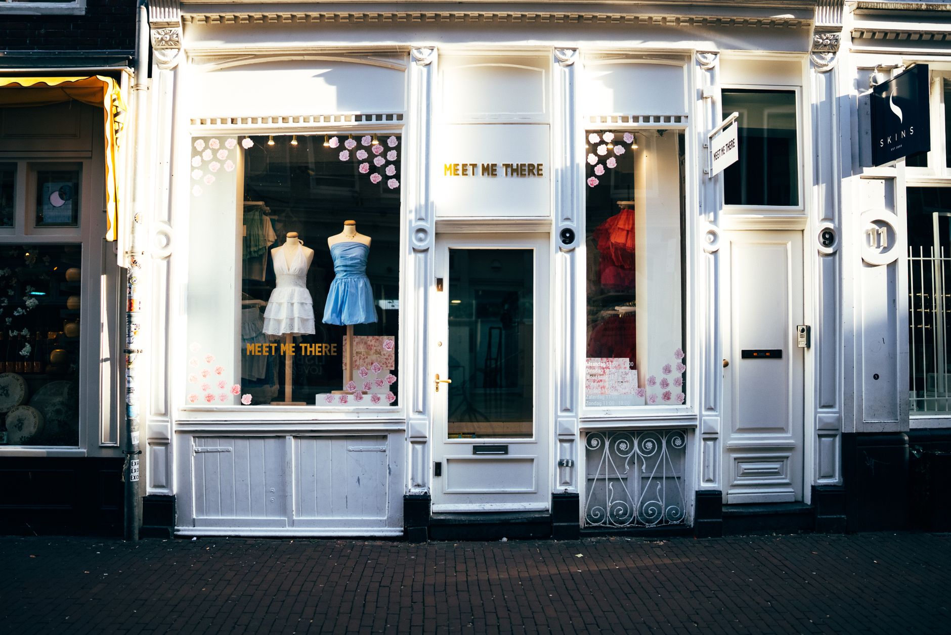 a retail boutique shopfront with a full-colour opaque vinyl decal displaying a seasonal sale message in bold typography against a white