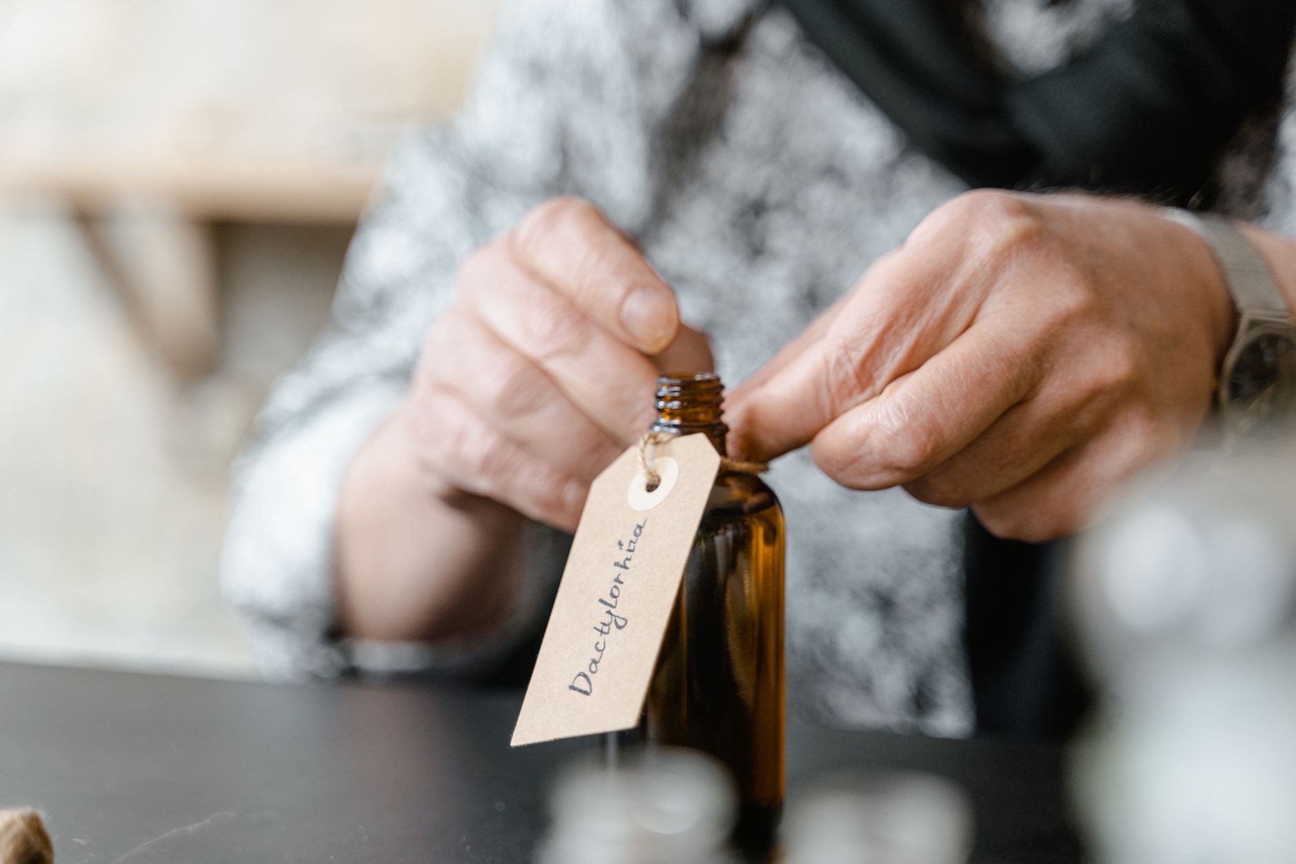 hands fastening a kraft paper label tag to a glass bottle
