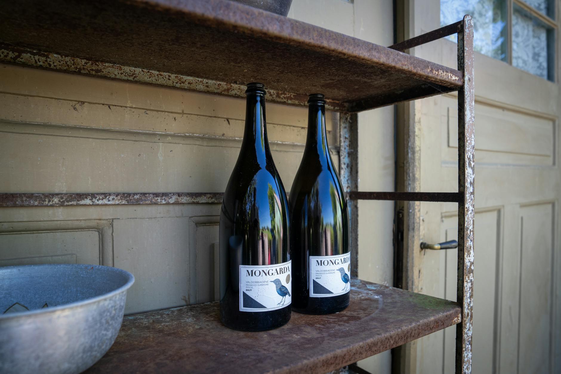 Side-by-side comparison of a paper wine label (showing bubbling and edge lift) next to a clear vinyl label on an identical bottle, both