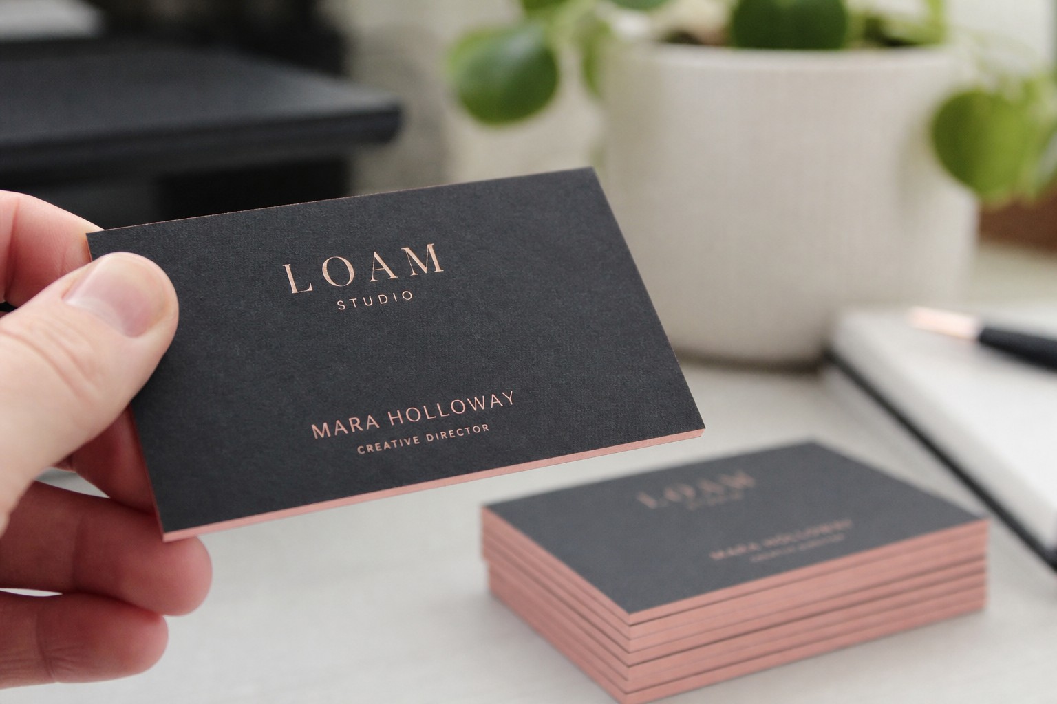 A close-up detail shot of a premium duplex business card held between two fingers