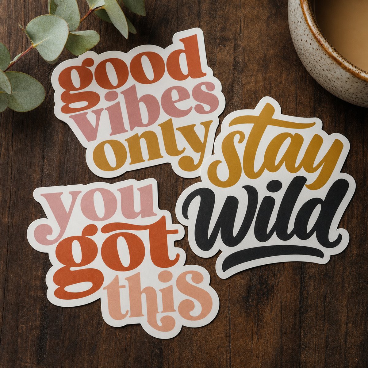 Die-cut stickers with bold typographic slogans on a walnut board, each cut to the exact outline with a clean white border