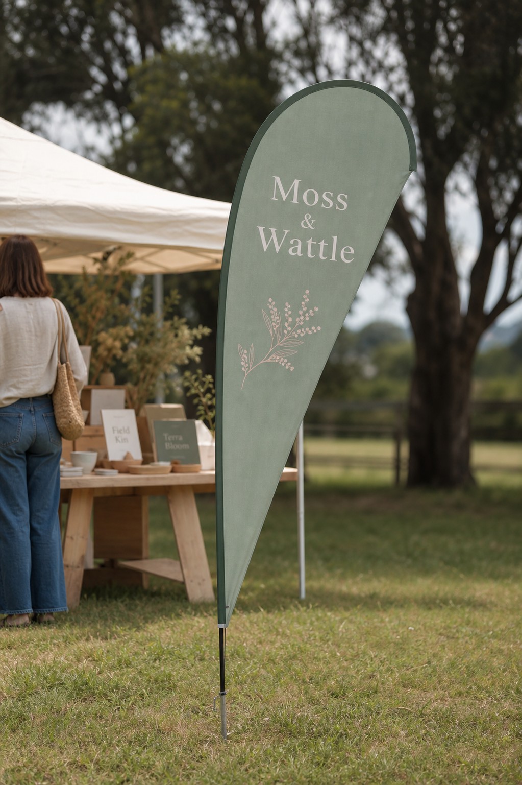 Teardrop banner flag · 125gsm trilobal fabric · dye-sublimated print · single-sided · on its free ground spike in grass