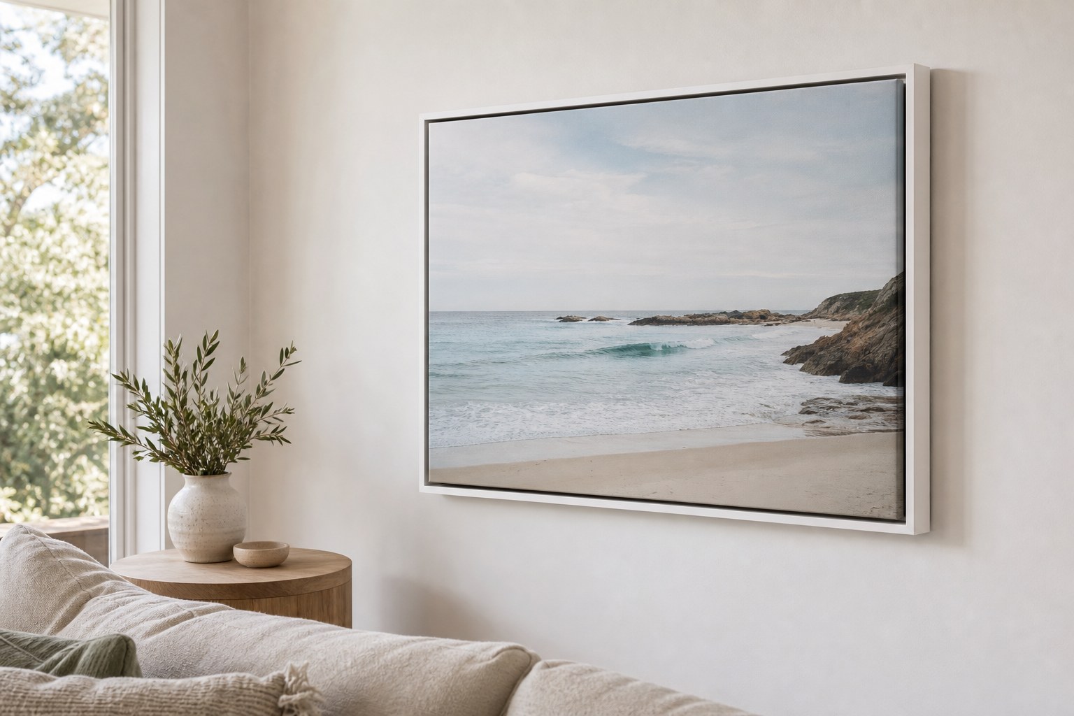 White floating frame canvas of a coastal scene on a pale living room wall