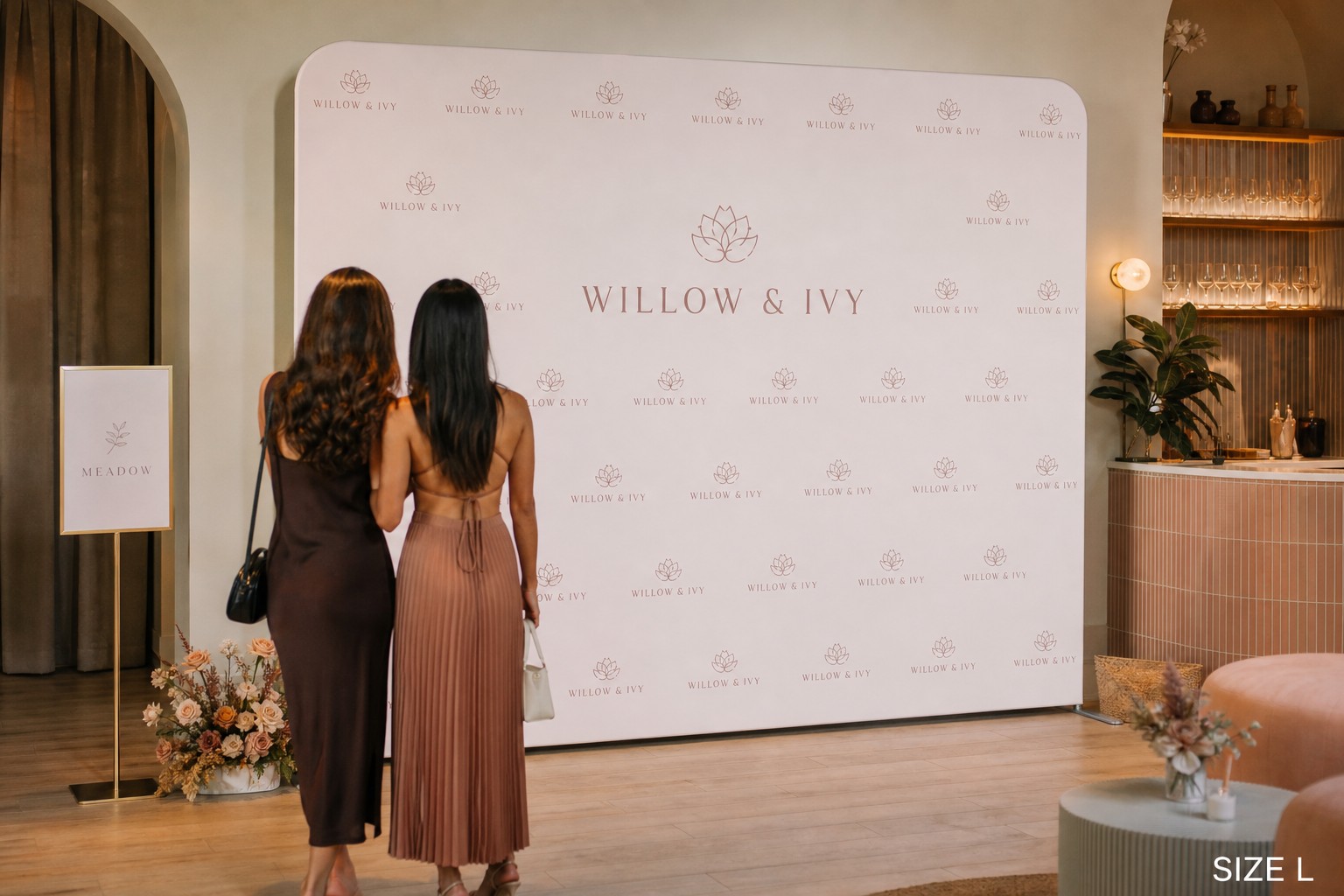 A branded stretch fabric media wall with a step-and-repeat logo pattern at a boutique launch event
