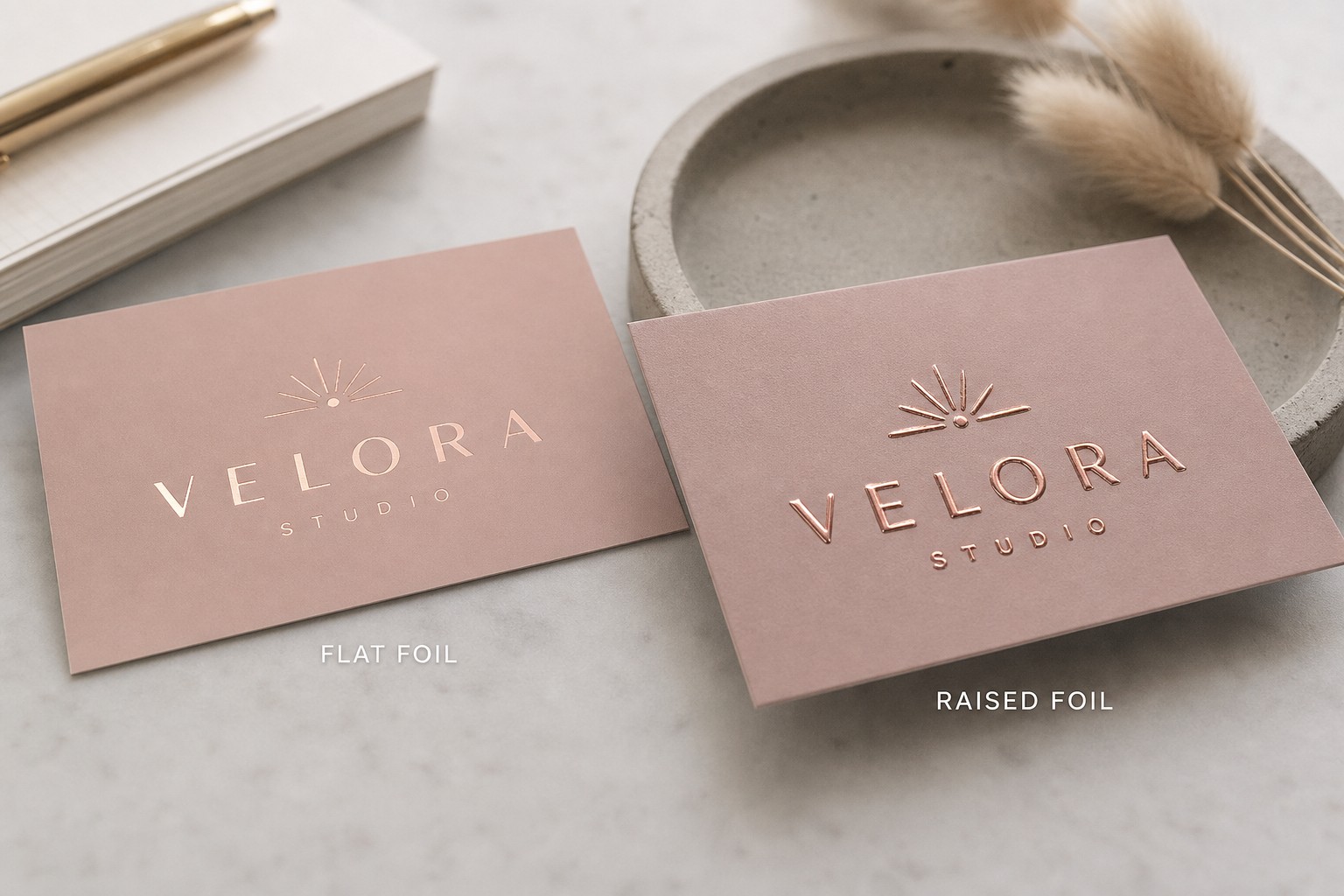 A close-up side-by-side comparing a flat rose gold foil business card and a raised rose gold foil business card