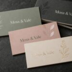 Premium finished business cards fanned on a dark surface · velvet laminate artboard · full-colour digital print · soft-touch matte, spot UV and raised-foil finishes