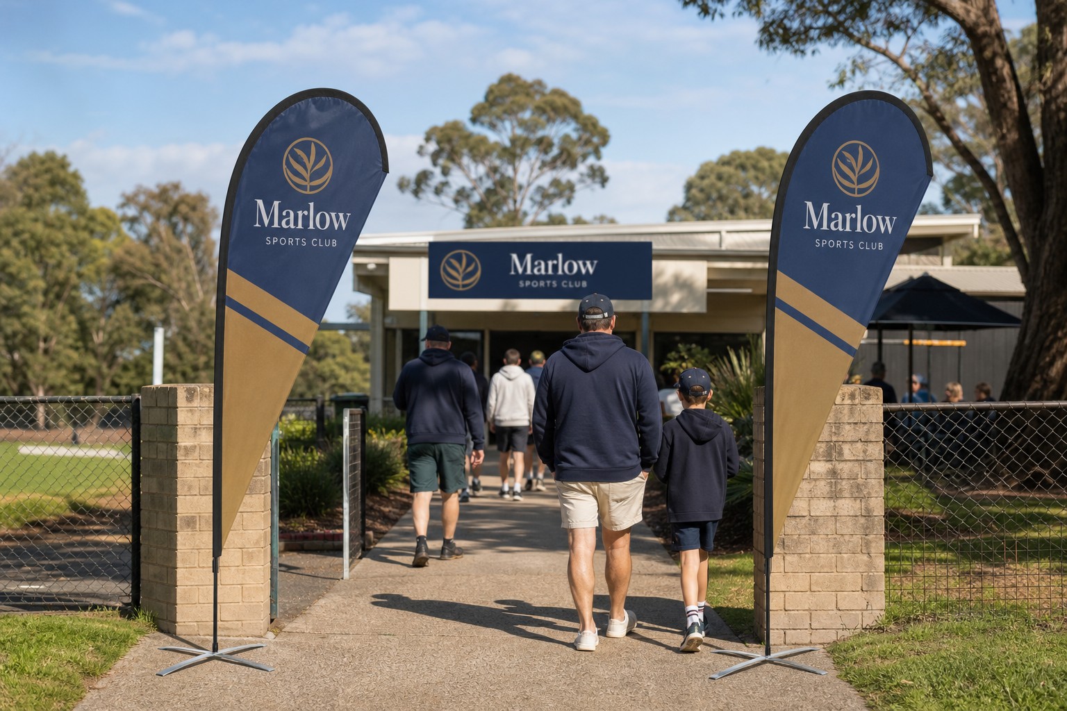 Two large teardrop banners planted either side of a suburban oval clubhouse entrance in club colours