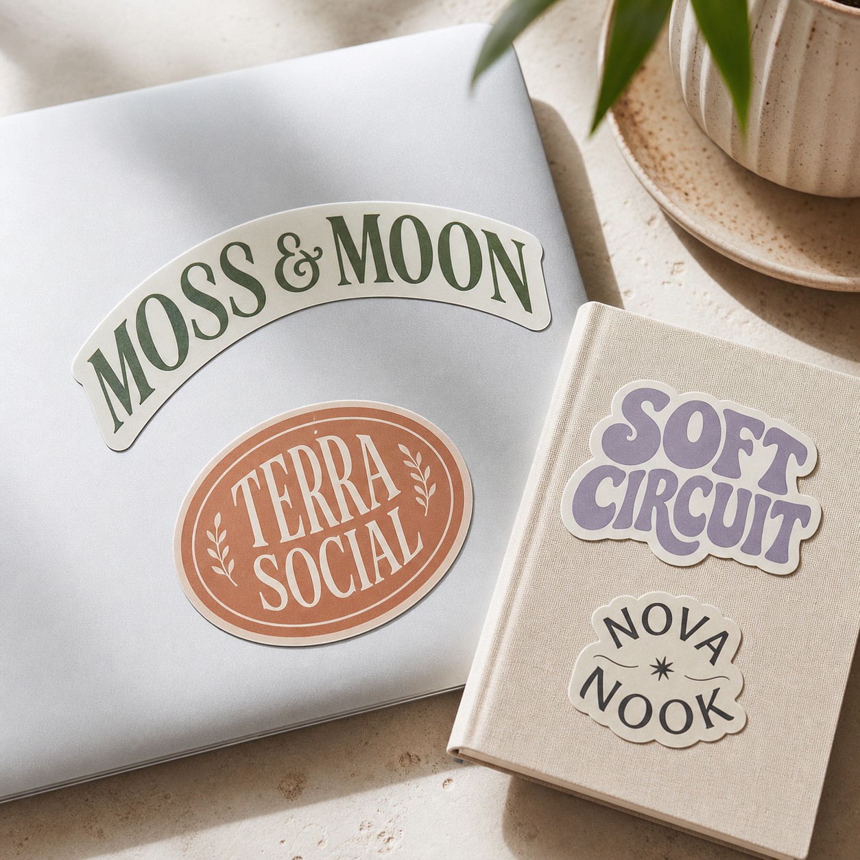 Brand logo die-cut stickers · adhesive sticker stock · full-colour digital print · matte finish · applied flat to a laptop lid and notebook