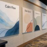 Printed foam board panels mounted on fabric display walls in a conference hall, a planter at left and an armchair at lower right, no people