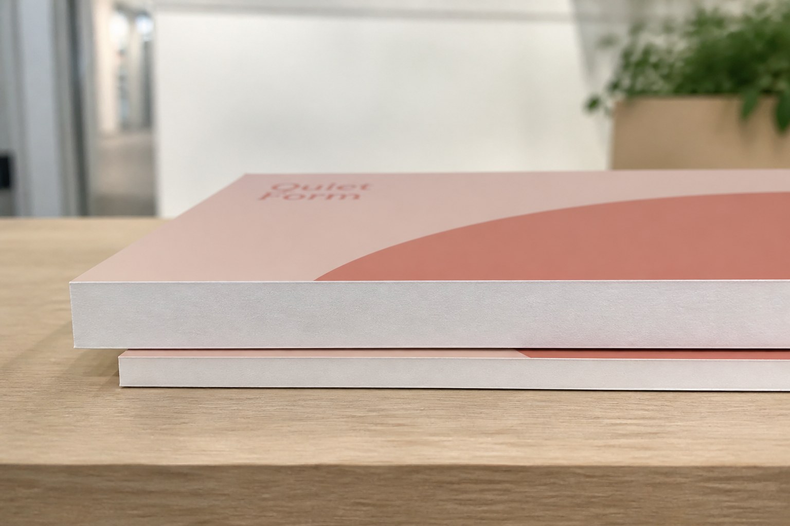 Two printed foam boards lie stacked offset on a pale timber bench, low angle showing the upper board's white core edge clearly deeper than the lower
