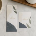 DL and A6 gift vouchers side by side on a white studio surface, one longer and narrower, both with the same calm design in shadowless light.