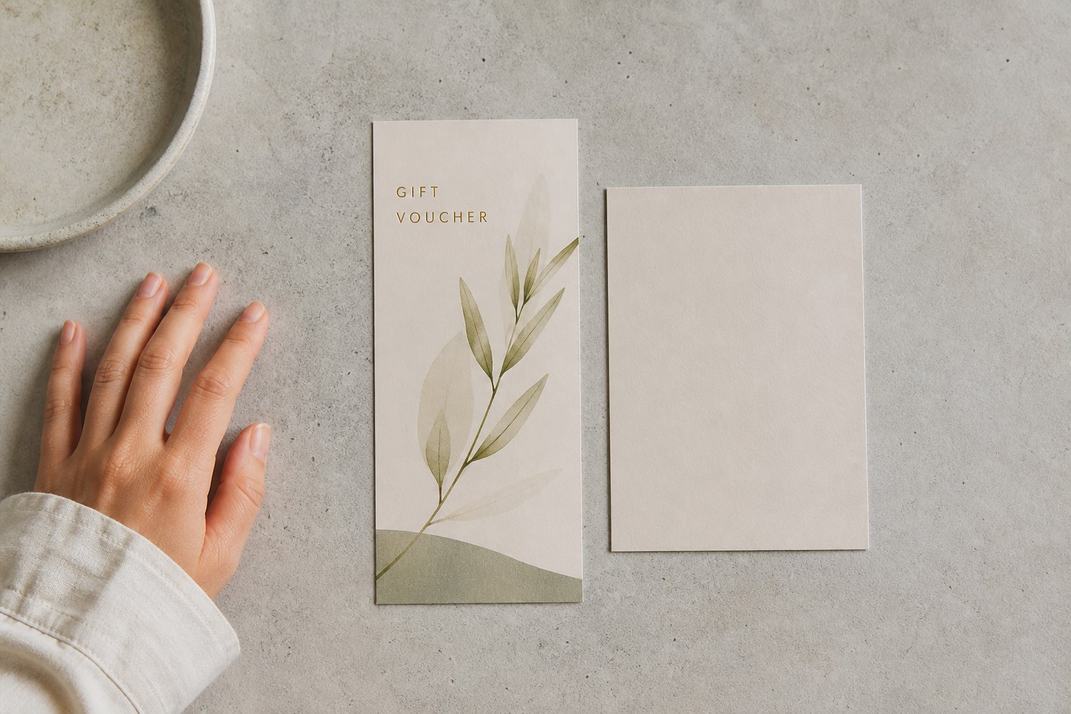 A short stack of identical A6 gift vouchers beside a plain manila folder on a light oak desk, with a cup of black coffee soft behind.