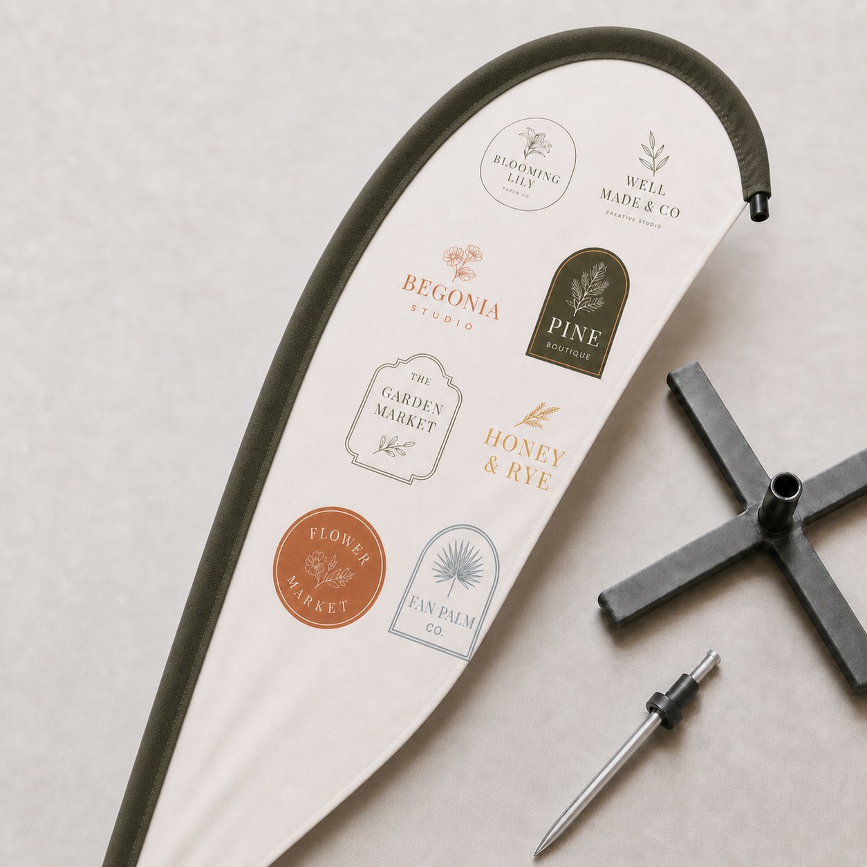 Teardrop flag skin laid out beside a black four arm cross base and a steel ground spike