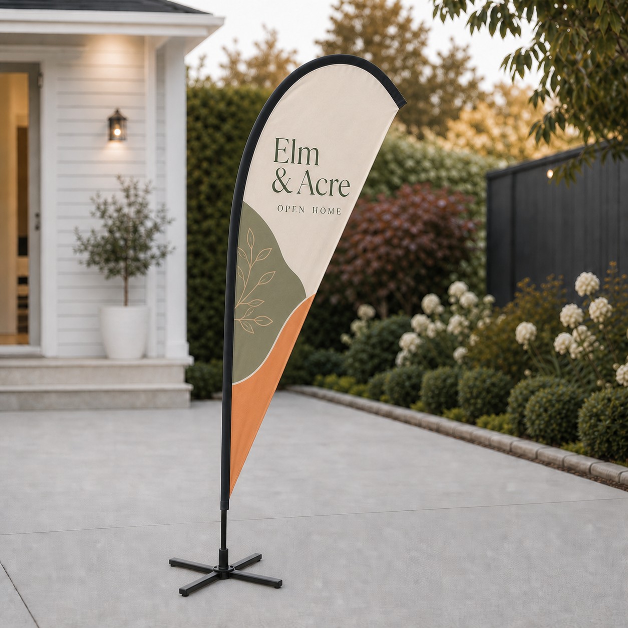 Teardrop flag standing on a concrete driveway on a black four arm cross base
