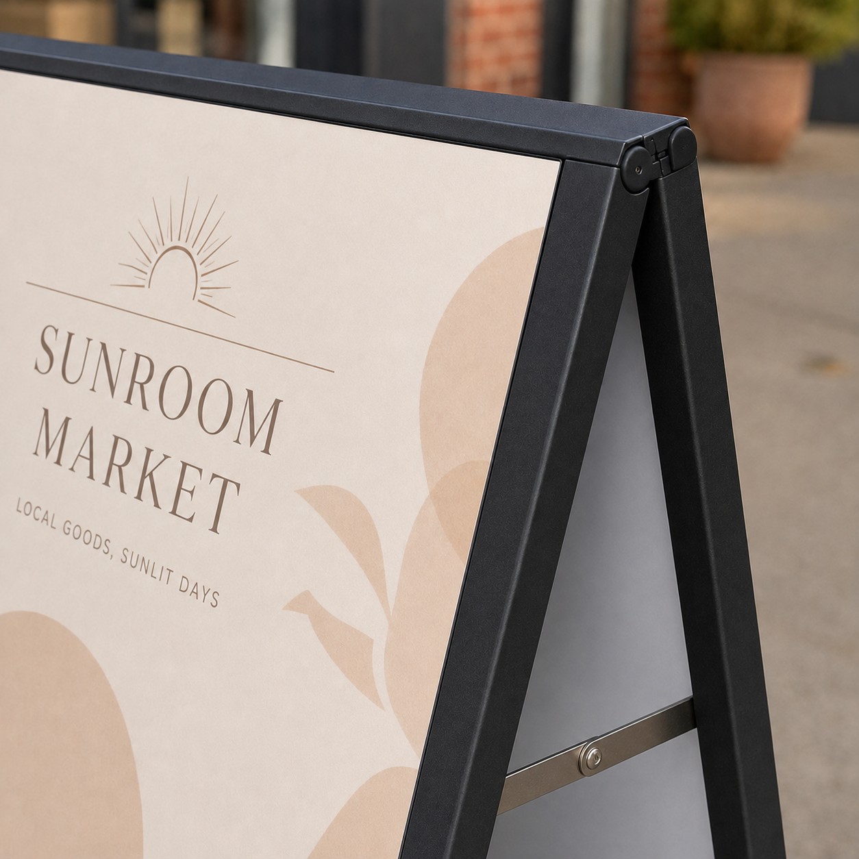 A-frame sign with black steel frame, top hinge, printed corflute panel sliding into side channel, silver strut at bottom, shopfront behind