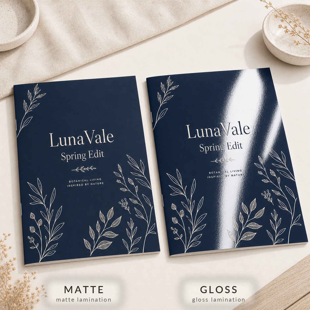 Two navy blue A4 booklets side by side with white botanical line drawing and matte and gloss laminated covers