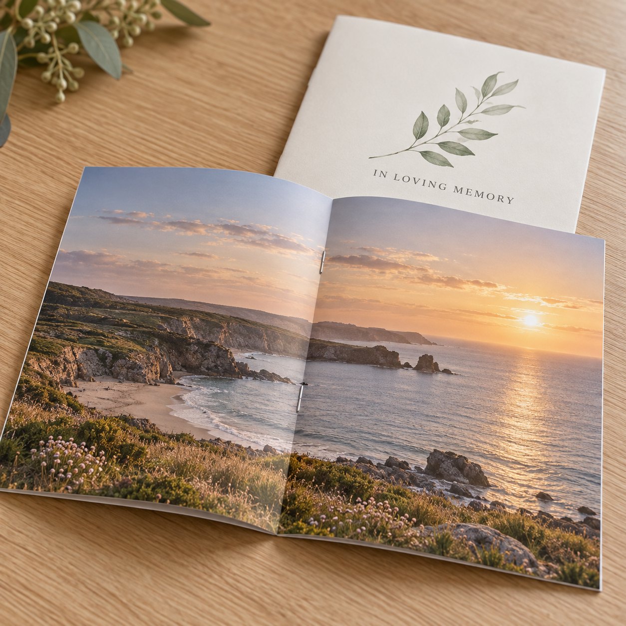 Close view of a funeral order of service booklet in A5 at centre spread with full bleed coastal photo and staples