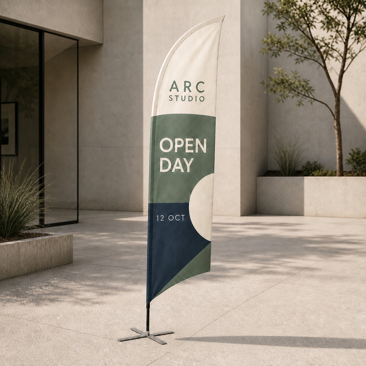 Bow banner with cream sage green and navy leaf print on a flexible pole with cross base in a courtyard outside a glass shopfront on paving.