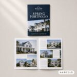 A closed navy brochure with a two-storey house and palm trees sits beside the same brochure opened flat on a warm off-white surface.