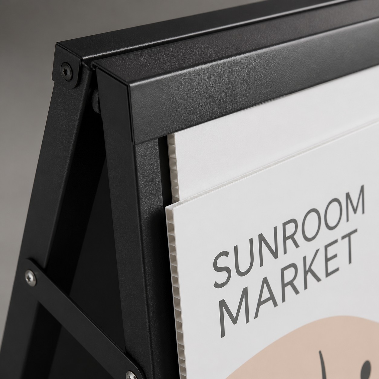 A-frame sign detail with black steel side channel open, corflute panel edge and fasteners visible, cream and black print, plain background