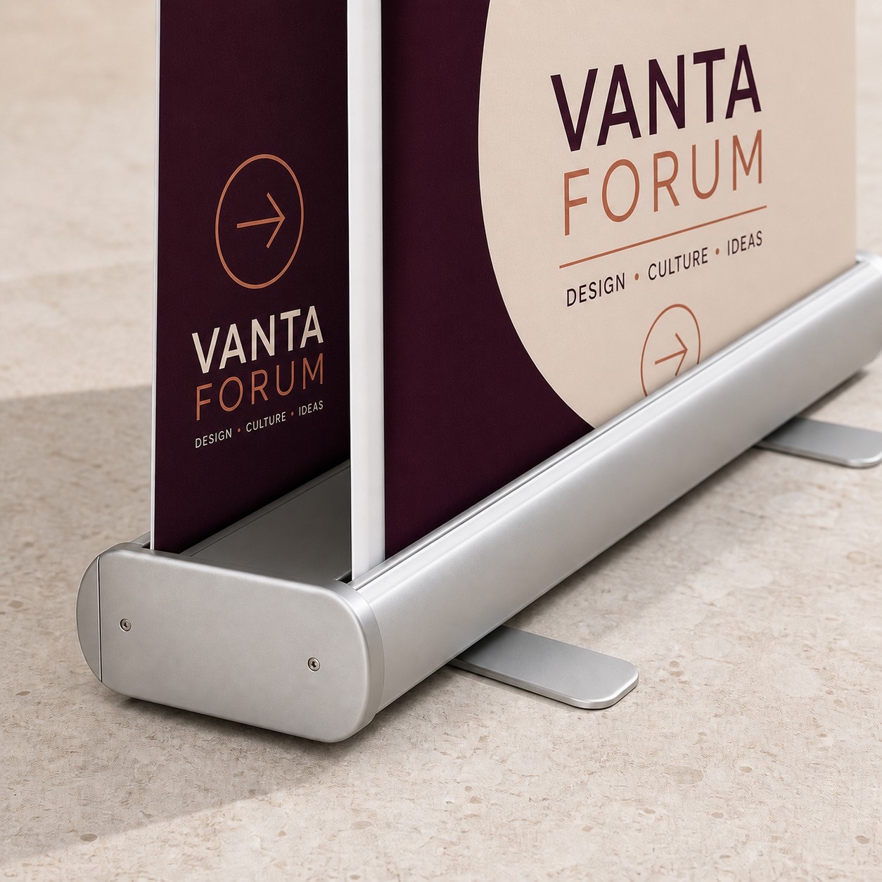 Double sided pull up banner with both sides visible, burgundy, white, copper and cream print, silver anodised cassette base on stone floor.