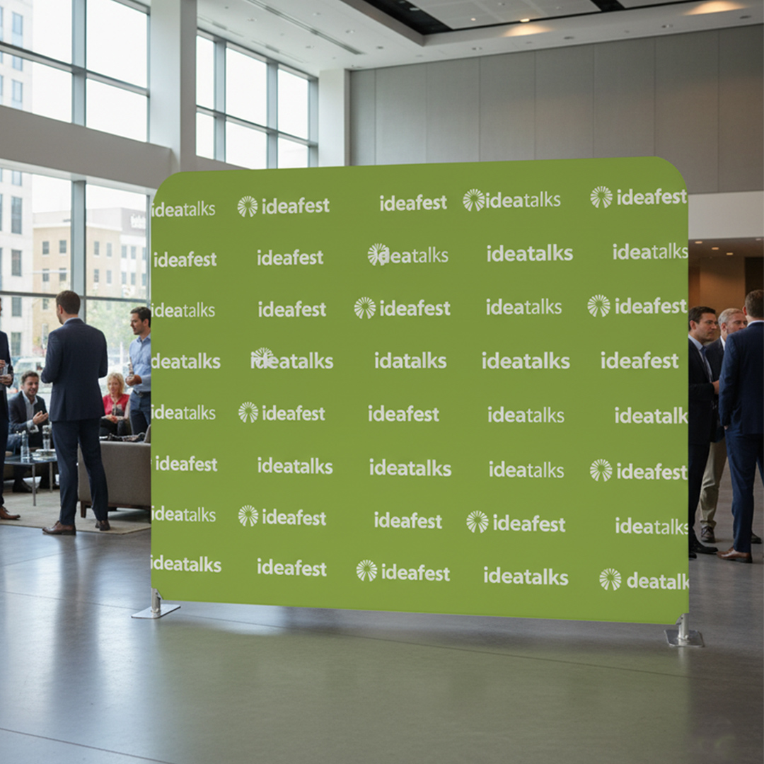 Lime green stretch fabric media wall with rounded top corners, printed with a white step and repeat logo pattern at an indoor event.
