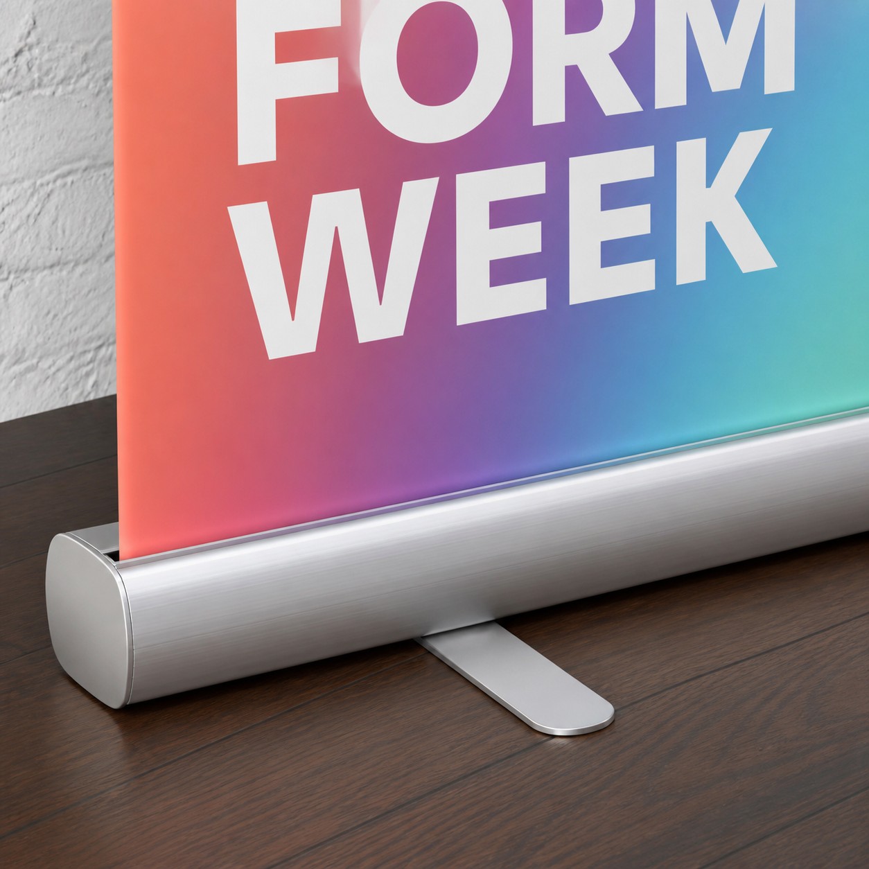 Pull up banner base close up with orange to cyan gradient print, silver anodised cassette base, roller drum and tension cable, printed text